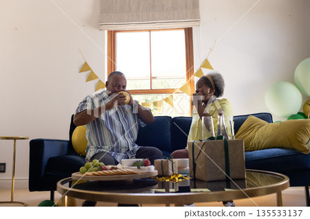 African American senior couple enjoying snacks and drinks at home celebration African American senior couple enjoying snacks and drinks at home celebration 135533137