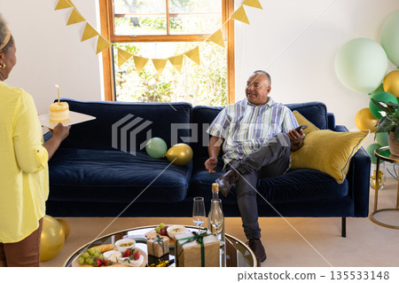 Celebrating birthday at home, African American man holding smartphone on sofa Celebrating birthday at home, African American man holding smartphone on sofa 135533148