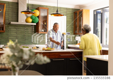 Senior couple preparing meal together in modern kitchen, enjoying conversation 135533166