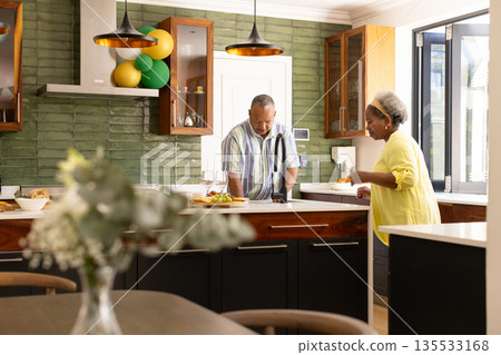 Senior couple enjoying cooking together in modern kitchen, sharing joyful moment 135533168