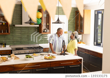Senior couple enjoying conversation in modern kitchen with fresh meal prepared 135533173