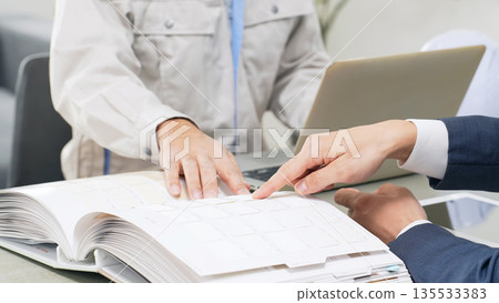A group of business people and workers having a meeting while looking at a catalog 135533383