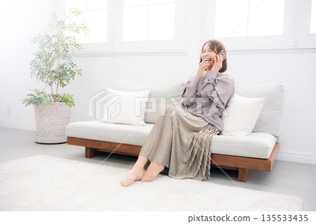 一位老年女性在房間裡用智慧型手機通話的全身像 135533435