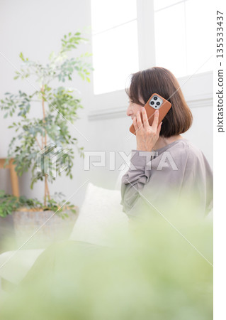 一位老年婦女在房間裡用智慧型手機通話的畫面 135533437