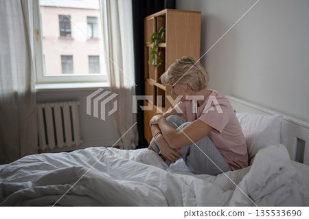 Sleepy unmotivated woman sitting in bed with tired expression, woke up early after restless night. 135533690