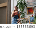 Talented artist female painter thinking looking at picture, creative inspirational working process. 135533693