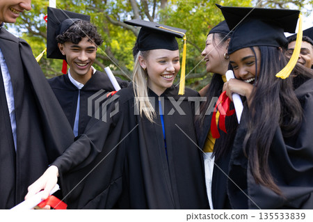 Graduating students in caps and gowns celebrating outdoors, smiling joyfully together Graduating students in caps and gowns celebrating outdoors, smiling joyfully together 135533839