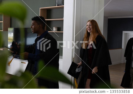 Teens in graduation gowns celebrating and smiling joyfully at home Teens in graduation gowns celebrating and smiling joyfully at home 135533858