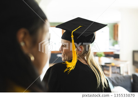 Graduating students wearing caps and gowns celebrating achievement at home Graduating students wearing caps and gowns celebrating achievement at home 135533870