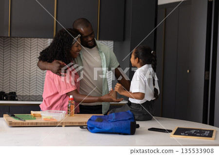 Family enjoying morning routine in kitchen, preparing for school with smiles 135533908