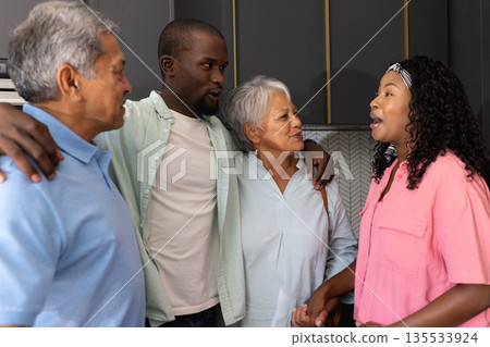 Family gathering at home, multigenerational members smiling and talking together Family gathering at home, multigenerational members smiling and talking together 135533924