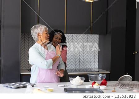 Baking in kitchen, African American woman and elderly woman sharing laughter together 135533928