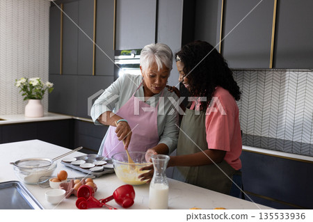 Baking together in kitchen, grandmother and granddaughter sharing joyful moment 135533936