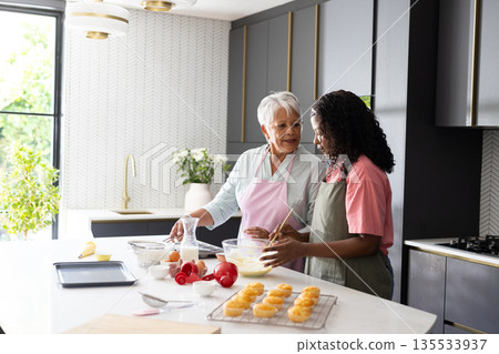 Baking in modern kitchen, African American woman and grandmother sharing joyful moment Baking in modern kitchen, African American woman and grandmother sharing joyful moment 135533937