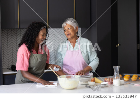 Baking together in kitchen, African American women sharing joyful moments and laughter 135533947