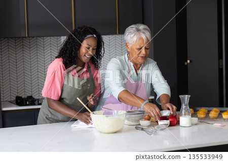 Baking together, grandmother and child sharing joyful moments in modern kitchen Baking together, grandmother and child sharing joyful moments in modern kitchen 135533949