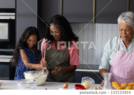 Three generations of women baking together in kitchen, sharing joyful moments 135533954