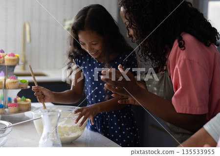 Mother and daughter baking together in kitchen, mixing ingredients with joy Mother and daughter baking together in kitchen, mixing ingredients with joy 135533955