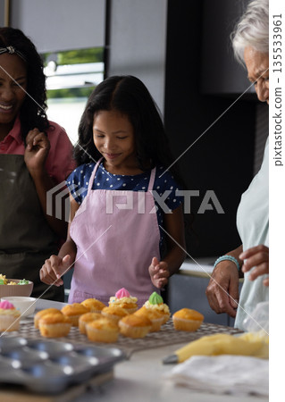 Baking cupcakes together, three generations smiling and sharing family time in kitchen Baking cupcakes together, three generations smiling and sharing family time in kitchen 135533961