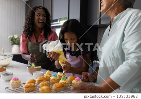 Baking cupcakes together, African American family sharing laughter and joy in kitchen 135533968