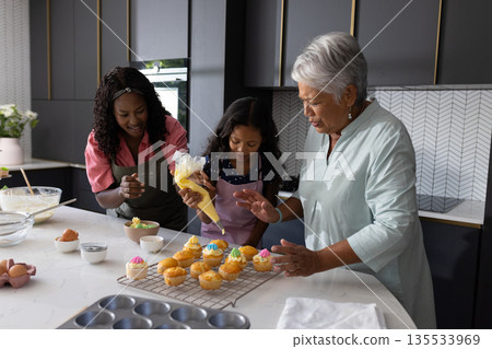 Decorating cupcakes in modern kitchen, three generations sharing joyful moments together Decorating cupcakes in modern kitchen, three generations sharing joyful moments together 135533969