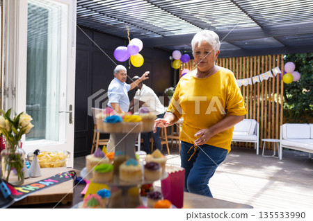 Grandmother enjoying colorful cupcakes at family birthday party on sunny patio Grandmother enjoying colorful cupcakes at family birthday party on sunny patio 135533990