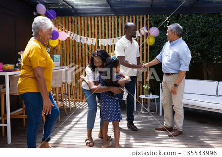 Outdoors, African American girl hugging mother, family smiling and greeting warmly Outdoors, African American girl hugging mother, family smiling and greeting warmly 135533996