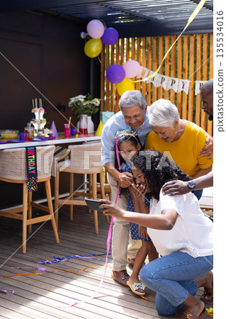 Family celebrating birthday outdoors, capturing joyful moment with smartphone selfie Family celebrating birthday outdoors, capturing joyful moment with smartphone selfie 135534016