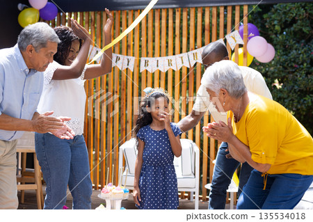 Celebrating birthday, African American girl with family at outdoor party together 135534018