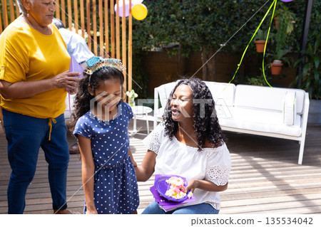 Celebrating birthday outdoors, African American mother and child smiling with family Celebrating birthday outdoors, African American mother and child smiling with family 135534042