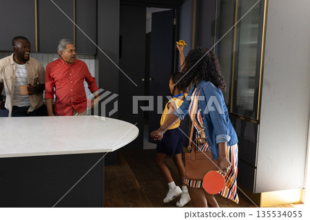 African American family celebrating in kitchen, holding trophy and smiling joyfully 135534055