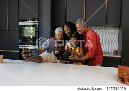 Family taking selfie together in modern kitchen, smiling and enjoying quality time 135534059