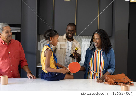 Family celebrating young girl's achievement with trophy and table tennis paddle 135534064
