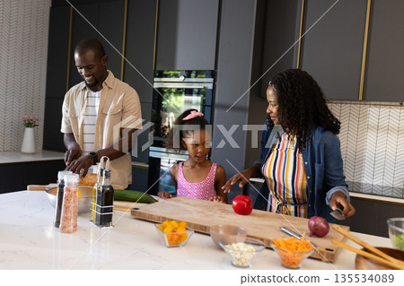 In kitchen, African American family preparing meal together, smiling and engaged In kitchen, African American family preparing meal together, smiling and engaged 135534089