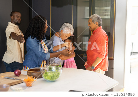 Three generations embracing warmly in kitchen, sharing love and laughter together 135534096