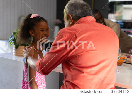Grandfather and granddaughter sharing joyful moment together in modern kitchen 135534100
