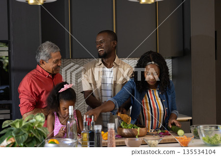 In kitchen, multigenerational family cooking and sharing laughter while preparing meal 135534104