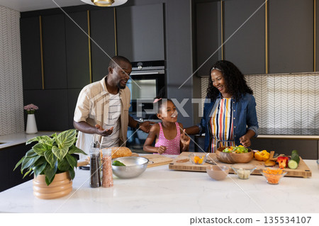 Family preparing healthy meal together in modern kitchen, sharing joyful moments Family preparing healthy meal together in modern kitchen, sharing joyful moments 135534107