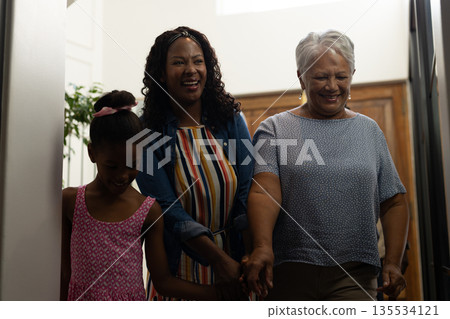 Three generations of women walking together at home, sharing joyful moments Three generations of women walking together at home, sharing joyful moments 135534121