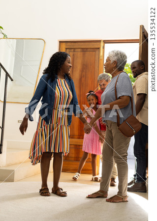 Family gathering, three generations warmly greeting each other at home entrance Family gathering, three generations warmly greeting each other at home entrance 135534122