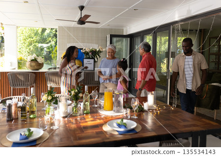On patio, three generations sharing laughter and conversation during family gathering On patio, three generations sharing laughter and conversation during family gathering 135534143