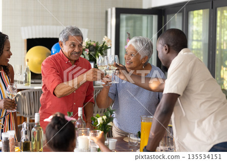 Family celebrating together, clinking glasses at home, enjoying joyful gathering Family celebrating together, clinking glasses at home, enjoying joyful gathering 135534151