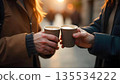 Two people hold coffee cups in the street, illustrating the warmth of friendship and kindness in everyday life 135534222