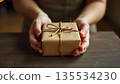 A person holds a wrapped gift box on a table, symbolizing kindness and generosity on World Kindness Day 135534230
