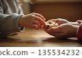 A child holds a cookie in the hands of an adult, illustrating kindness, care, and the importance of giving 135534232