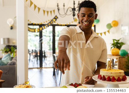 Man reaching for fruit plate in home dining and living space, celebrating birthday with cake 135534463