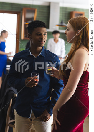 Teenagers having drinks and chatting at lively school party gathering 135534808