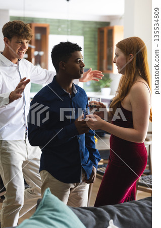 Teen friends celebrating at home, enjoying drinks and lively conversation together 135534809