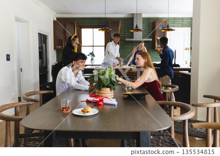 Teenagers celebrating at home, enjoying food and conversation around dining table Teenagers celebrating at home, enjoying food and conversation around dining table 135534815