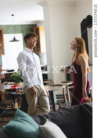 Teenagers laughing and enjoying drinks at home during lively celebration 135534818